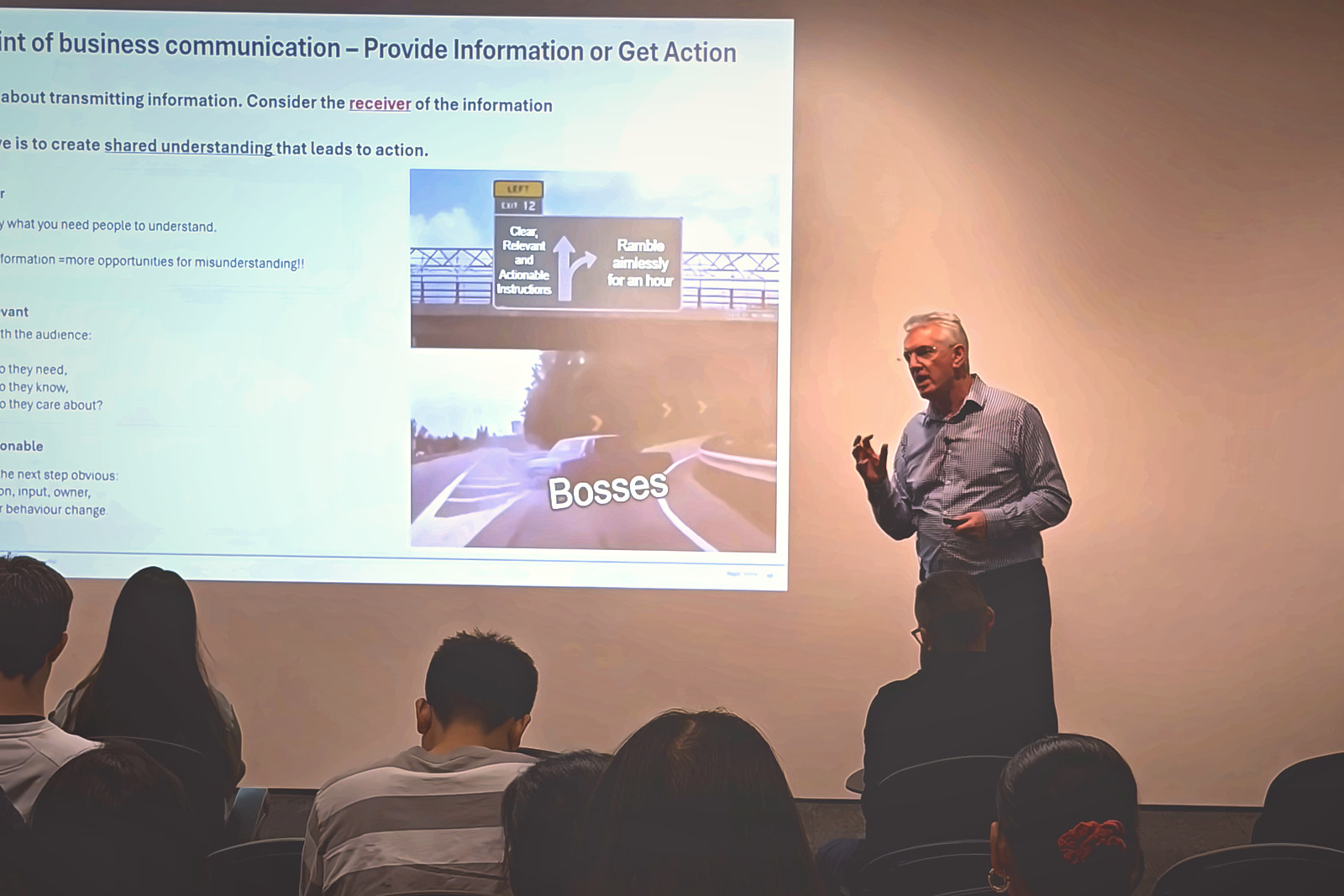 A keynote speaker presenting on workplace communication at Comedy Summit Global 2026